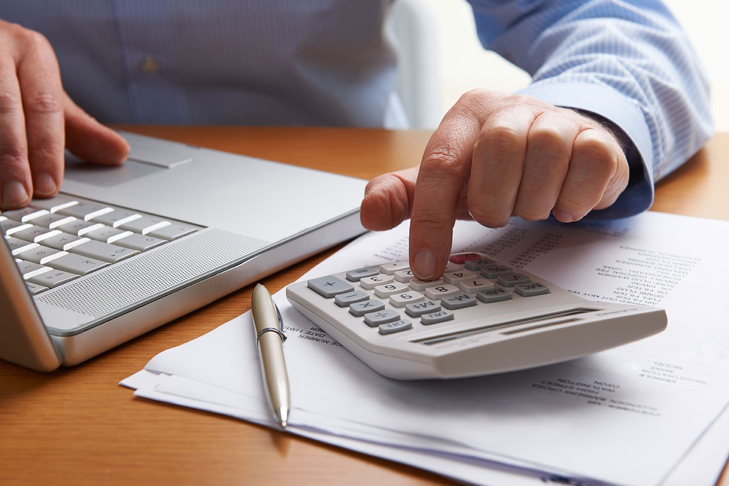 Male hands calculating bills on a calculator.